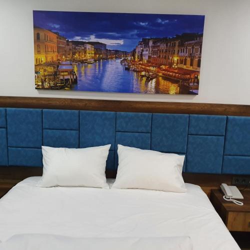 a bedroom with a white bed and a painting on the wall at seyir yeri otel cafe&restorant in Trabzon