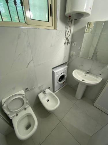 a white bathroom with a toilet and a sink at Eagle’s Nest in Shkodër