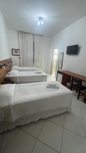a room with three beds and a television in it at Atlântico Hotel in Santos