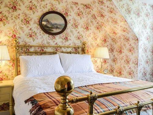 a bedroom with a bed with floral wallpaper at Beautiful Traditional secluded country cottage in Sanquhar