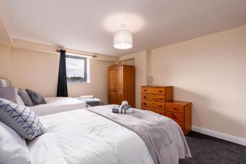 a bedroom with two beds and a dresser and a window at Cosy Apartment & Central Location & Contractors & DSA in Doncaster