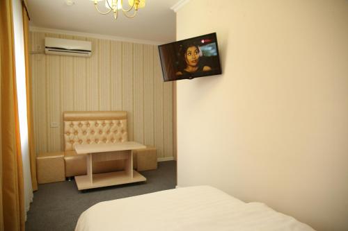 Habitación con cama y TV en la pared. en Sweet Home Hotel en Atyraū