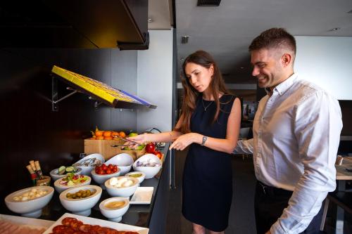 a man and woman standing in a kitchen preparing food at Hotel Vilamarí in Barcelona
