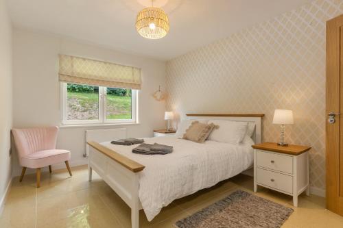 a bedroom with a bed and a chair and a window at Parsonage Cottage- Peaceful, Dog Friendly Cottage in Begelly
