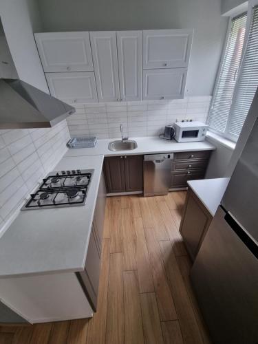 a white kitchen with a stove and a sink at Apartment By The Sheraton in Batumi