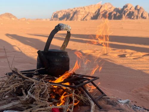 a pot sitting on top of a fire in the desert at Sand Star Camp in Wadi Rum