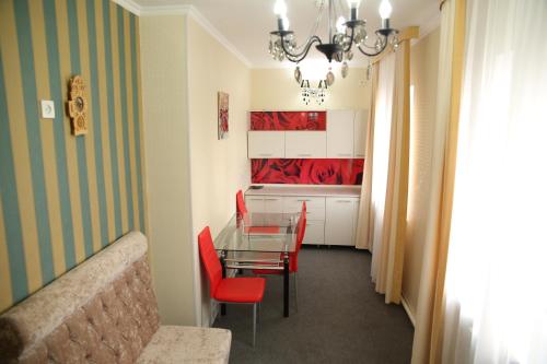 a dining room with a table and red chairs at Sweet Home Hotel in Atyraū