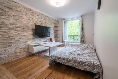 una camera da letto con un muro di mattoni, un letto e una scrivania di logement cosy et moderne proche de toute commodité a Parigi