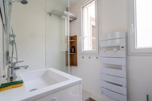 a white bathroom with a sink and a window at logement cosy et moderne proche de toute commodité in Paris