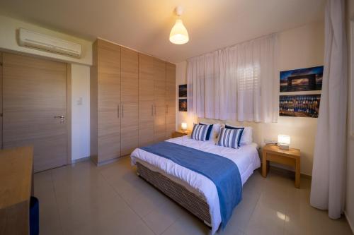 a bedroom with a bed with blue and white pillows at No.7 Athena Beach Villa, Pernera in Paralimni