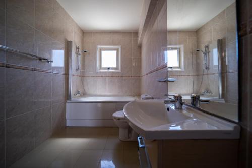 a bathroom with a sink and a tub and a toilet at No.7 Athena Beach Villa, Pernera in Paralimni