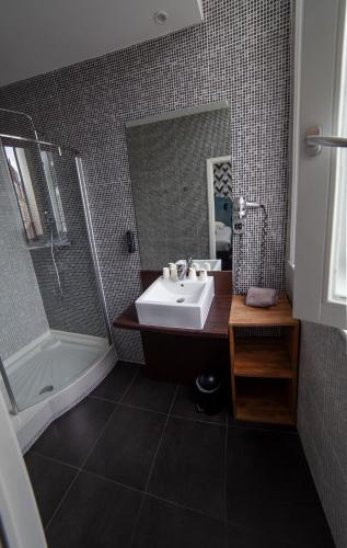 a bathroom with a sink and a tub and a mirror at Hotel Kanaï in Lille