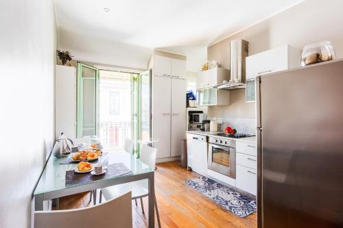 une cuisine avec un réfrigérateur en acier inoxydable et une table dans l'établissement LUNG ARNO AP4300 By Riviera Holiday Homes, à Nice