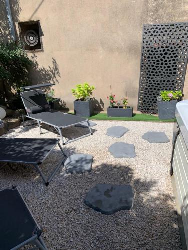 a patio with a chair and a table and some plants at Les dahlias appartement 4 personnes Jacuzzi Barbecue Jardin arboré Climatisé in Agde