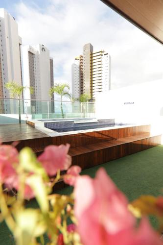 einen Balkon mit Stadtblick und rosafarbenen Blumen in der Unterkunft Premium Flat Ponta Negra Natal in Natal