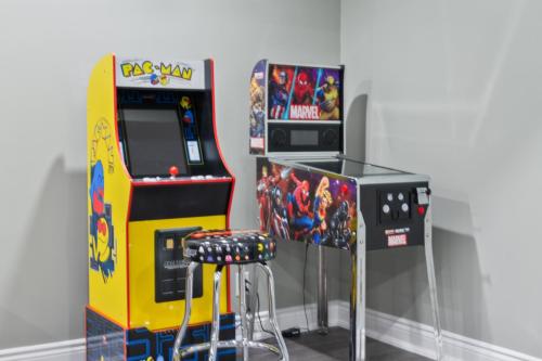 a video game arcade machine next to a bar stool at Modern home with a pool sauna pooltable & mountain view in Collingwood