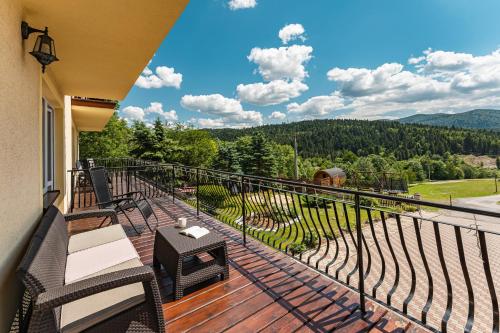 a balcony with wicker chairs and a view of the mountains at Pod Horodkiem in Cisna