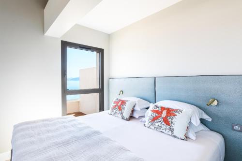 a bedroom with a bed with pillows and a window at RESIDENCE SANTA MARIA in LʼÎle-Rousse