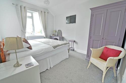 a bedroom with a bed and a chair and a window at Broadlands Guest House in Stratford-upon-Avon