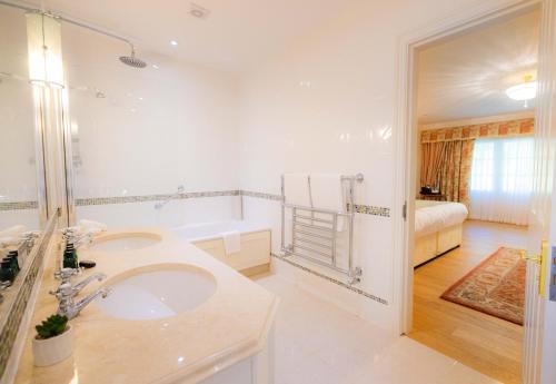 a white bathroom with a sink and a tub at The Dixcart Hotel in Sark