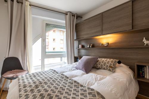 a bedroom with a bed and a large window at APPARTEMENT CENTRE VILLE PARKING COUVERT WIFI BALCON in Cauterets