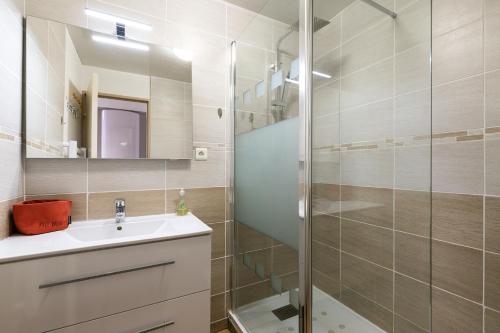 a bathroom with a sink and a glass shower at APPARTEMENT CENTRE VILLE PARKING COUVERT WIFI BALCON in Cauterets