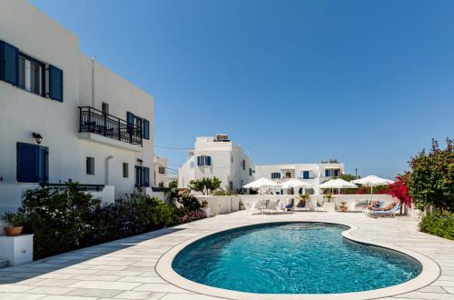 a swimming pool in a courtyard with white buildings at Ikaros Studios & Apartments in Naxos Chora