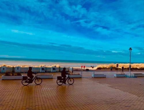 two people are riding bikes on the beach at Appartement moderne de 94 m² 2 ch. sur la digue in Nieuwpoort