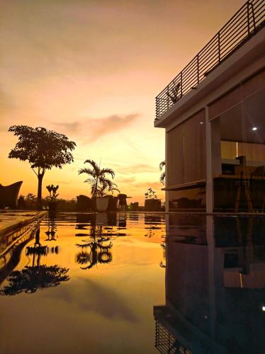 a pool of water in front of a building at sunset at Garden House Jepara in Jepara