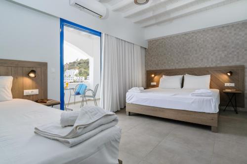 a hotel room with two beds and a balcony at Kyma in Loutro