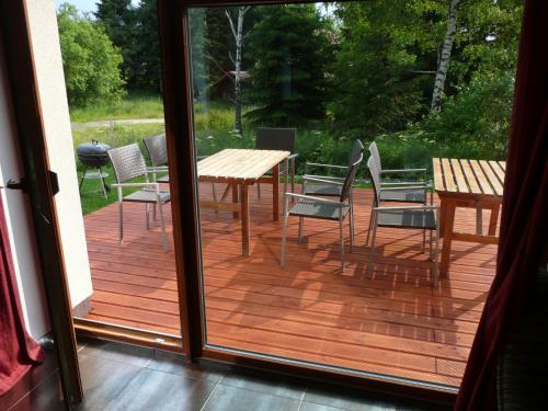 a wooden deck with chairs and a table and tables at Chata Marta in Boží Dar