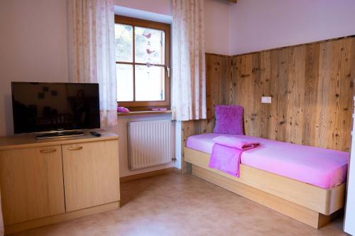 a small bedroom with a bed and a television at Garberhof-Stocker in Campo Tures