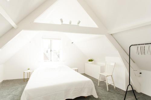 biała sypialnia na poddaszu z łóżkiem i oknem w obiekcie Amazing and stylish house near city center Dordrecht, close to Rotterdam w mieście Dordrecht