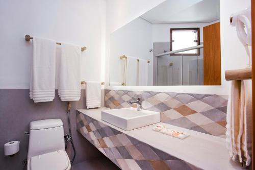 a bathroom with a sink and a toilet and a mirror at Hotel Real Villa Bella in Ilhabela