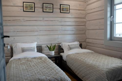 two beds in a room with wooden walls at Góry Świateł in Krynica Zdrój