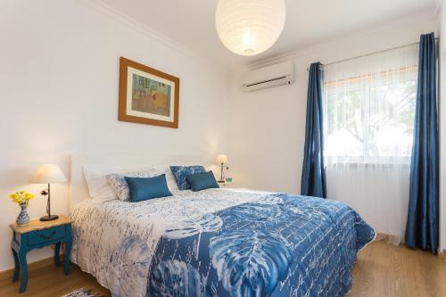 sypialnia z niebiesko-białym łóżkiem i oknem w obiekcie Dream holidays @ Santa Luzia Tavira w mieście Santa Luzia