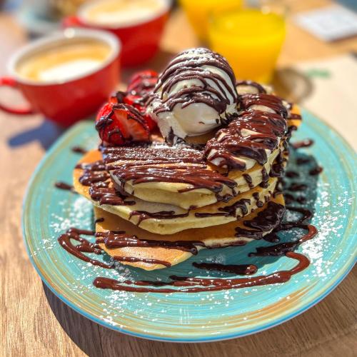 a stack of pancakes with chocolate and strawberries on a blue plate at Aris Grand Place Hotel in Brussels