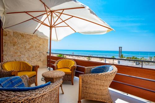 un balcón con sillas y sombrilla y la playa en DELPOSTO Marina di Ragusa (elt), en Marina di Ragusa