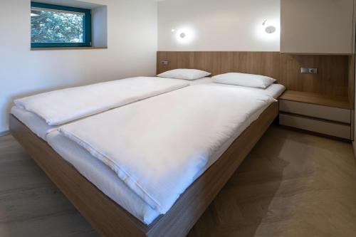 a large bed with white sheets in a bedroom at Apartmány Na Zahradách in Lednice