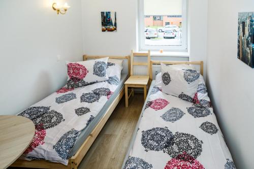 two beds in a room with a table and a window at Hazel Apartment in Vilnius