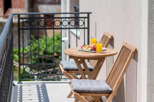 einen Tisch mit zwei Stühlen und zwei Tassen Orangensaft in der Unterkunft Luxury Apartments Ivanovic in Tivat