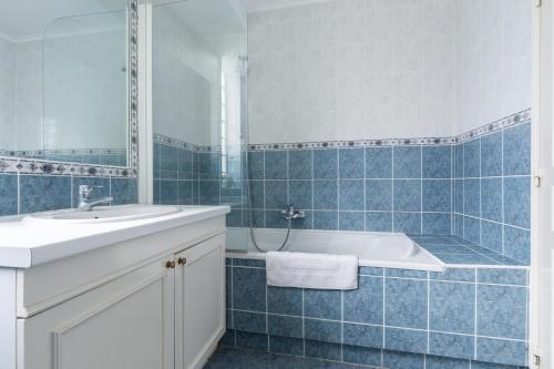 La salle de bains est pourvue de carrelage bleu, d'une baignoire et d'un lavabo. dans l'établissement Bright two bedroomed apartment on the beach in Cannes with huge terrace with fabulous sea views - 2001, à Cannes