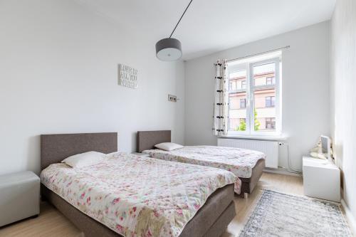 two beds in a white room with a window at Old Town Hearh Light and Open Modern Flat VIP in Klaipėda