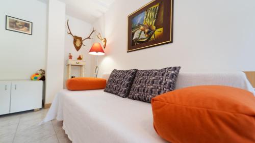 a bedroom with a white bed with an orange pillow at Karolina in Fužine