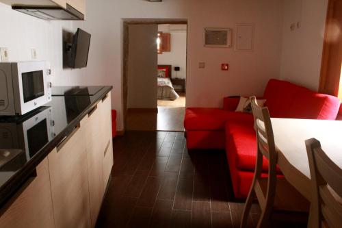 a kitchen and a living room with a red couch at Casas do Fantal in Vale de Salgueiro