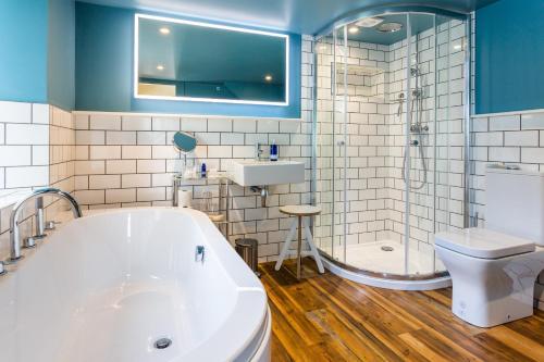 a bathroom with a tub and a toilet and a sink at Cruickshanks Boutique B&B in Whiting Bay