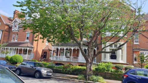 a group of houses with cars parked in front of a tree at Beautiful Garden Apartment in Leafy St Leonards 5 Mins to Beach in St. Leonards