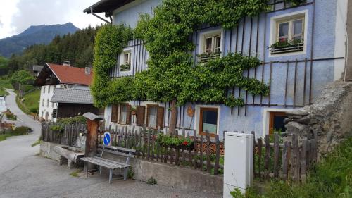 a blue house with a wooden fence and a bench at Ferienwohnung Jörgenhof in Telfes im Stubai