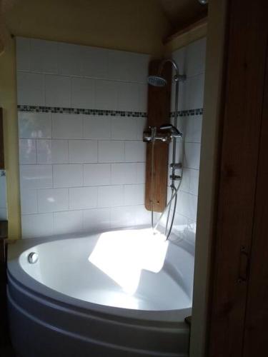 La salle de bains est pourvue d'une baignoire et d'un mur en carrelage blanc. dans l'établissement Le Studio, à Saint-Augustin