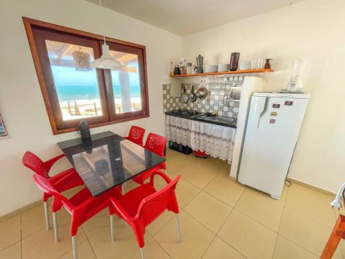 cocina con mesa, sillas rojas y nevera en URUAÚ BEACH RESIDENCE, en Beberibe